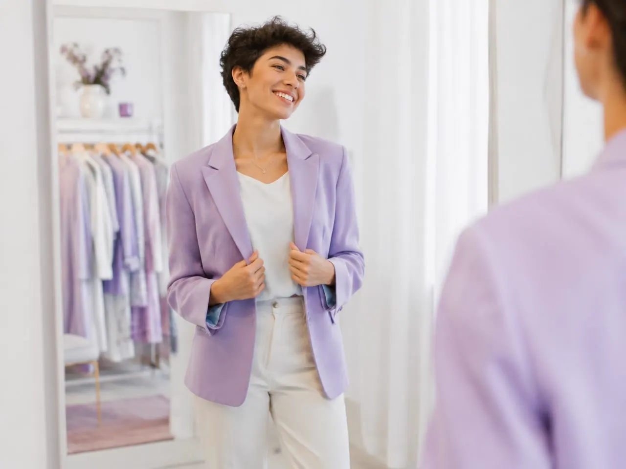 Smiling guest trying on a blazer in front of a mirror